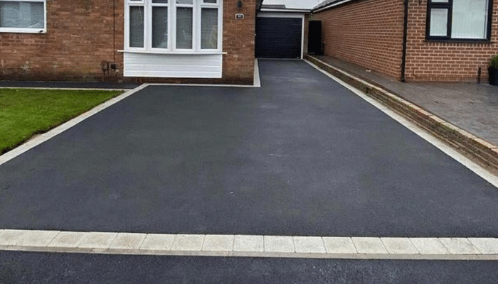 New tarmac driveway with stone edging at a brick-built house
