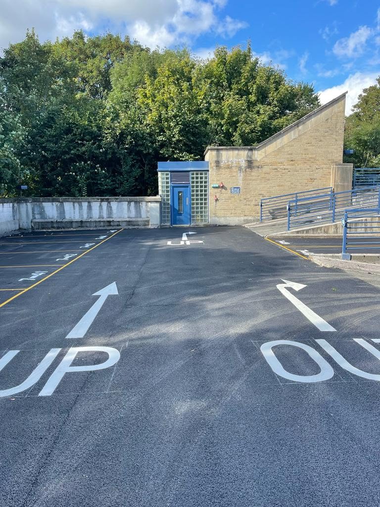 Resurfaced car park entrance with UP and OUT road markings