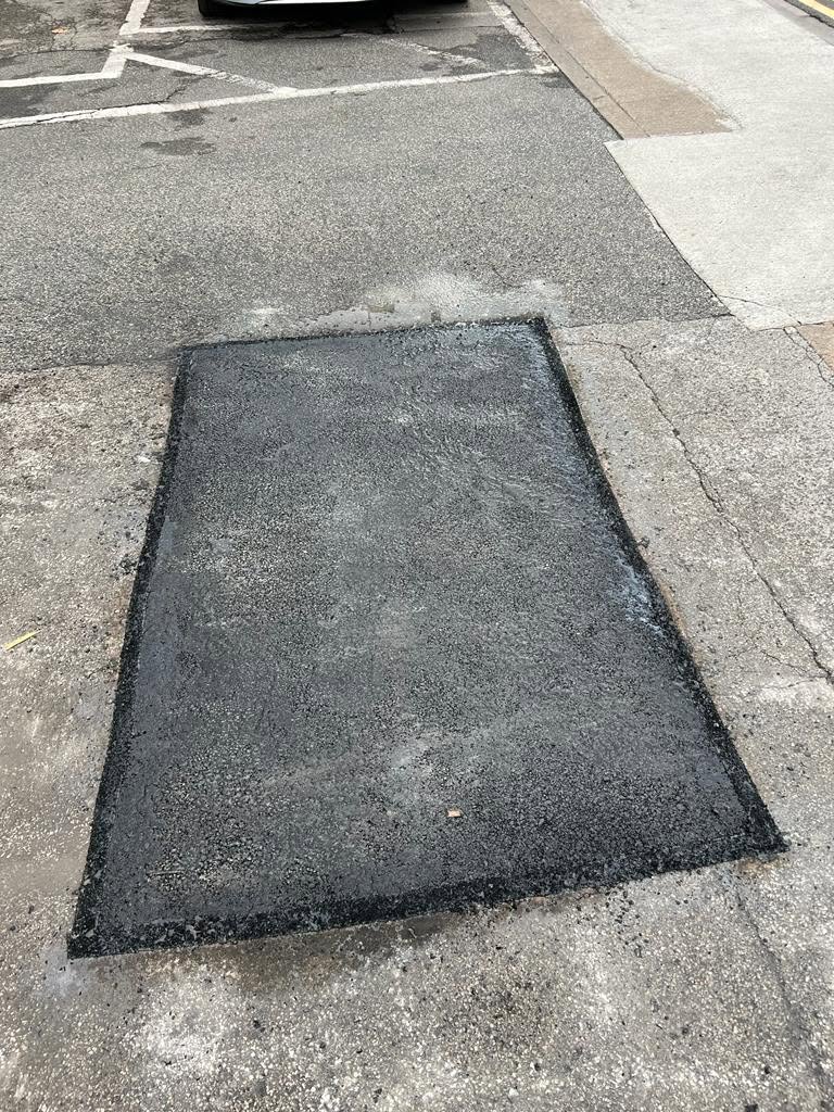 Neat tarmac patch repair in a car park