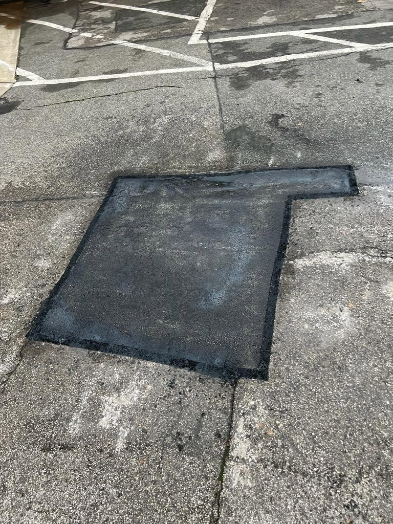 Tarmac patch repair around a worn area, edges sealed